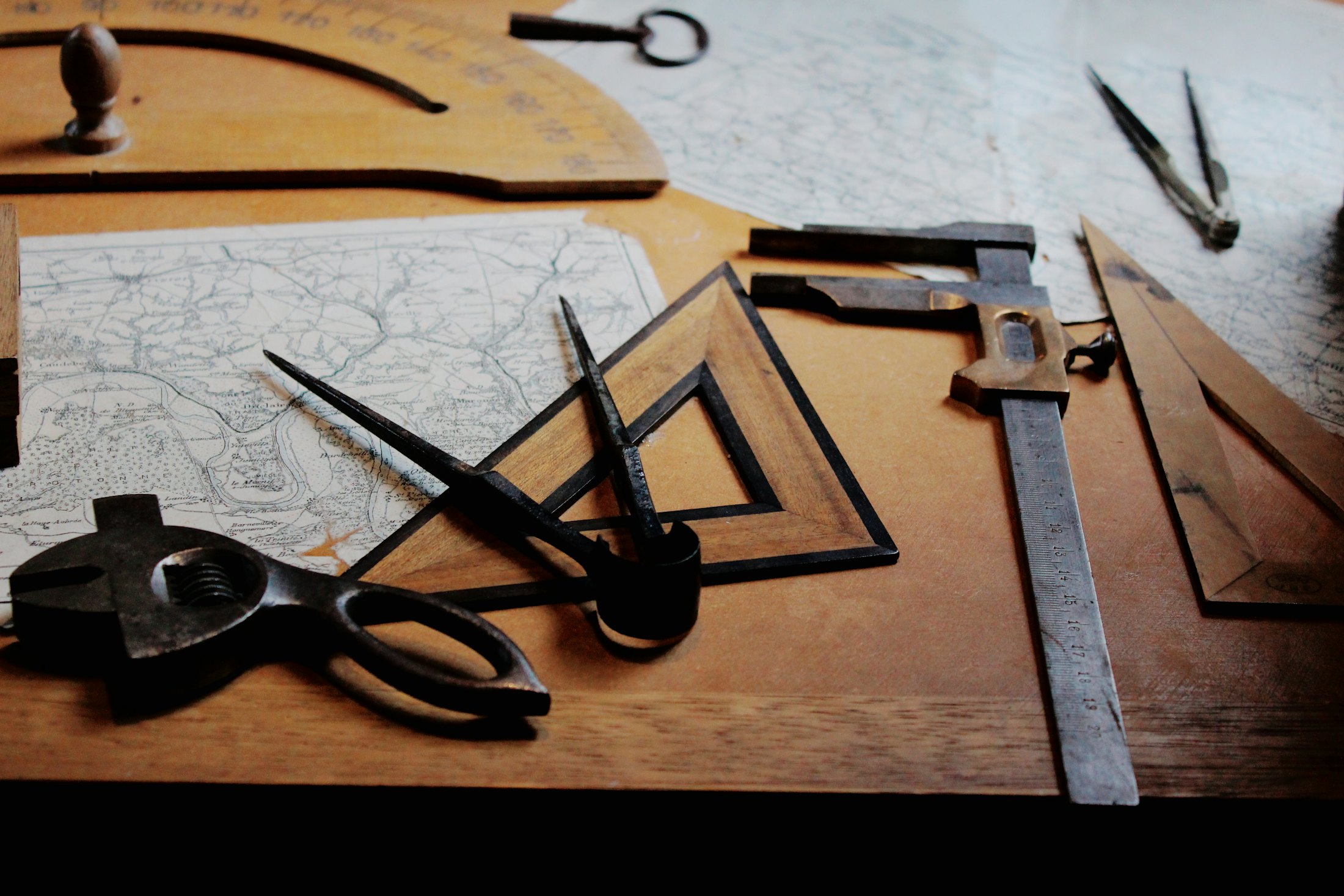 Drafting tools, a compass and set squares spread across a wooden table